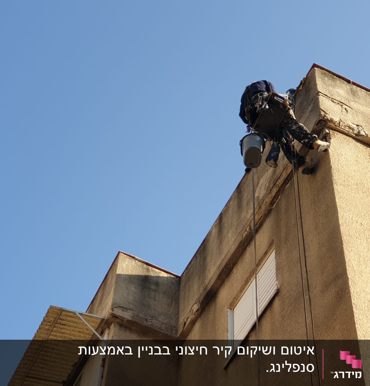 אדם על חבל אוטם קיר חיצוני של בניין